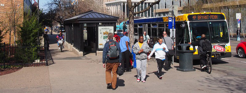 People walking and bicycling near a bus